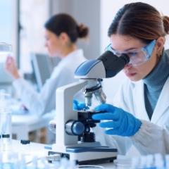 Women in lab looking through microscope